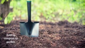 Photo shows a shovel in the ground preparing to work compost into the soil. 